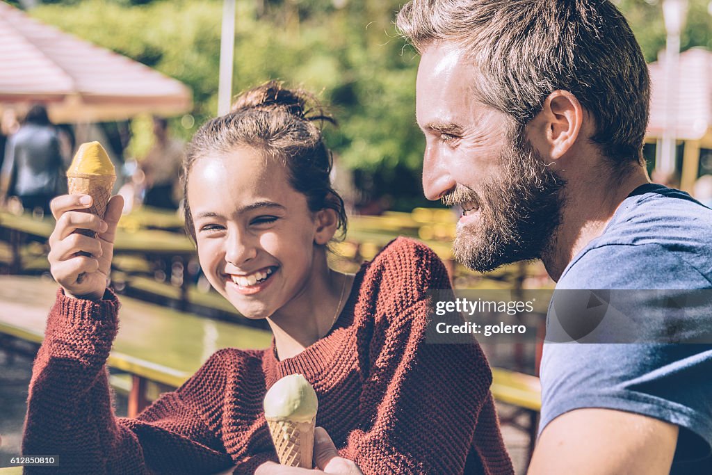 Glücklicher Vater und seine Tochter essen Eis im Freien