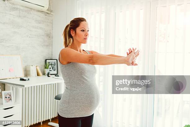 pregnant woman exercises yoga in her livingroom. - breathing new life stock pictures, royalty-free photos & images