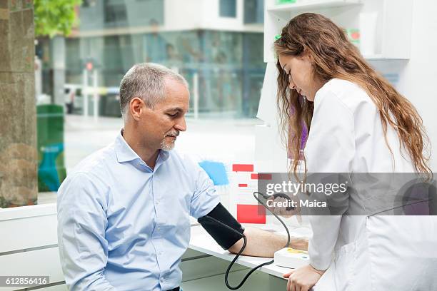 girl taking blood pressure to mature man - outpatient care stock pictures, royalty-free photos & images
