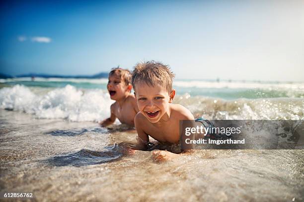 ragazzini sdraiati sulla spiaggia in mare e ridendo - two young boys foto e immagini stock