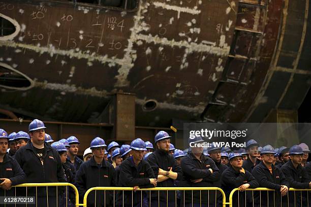 Workers listen as Britain's Defence Secretary Michael Fallon speaks after watching the first piece of steel for the successor submarine programme...