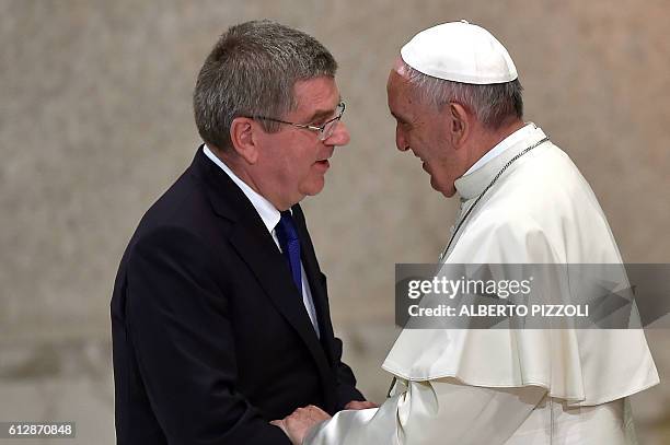 Pope Francis shakes hands with International Olympic Committee President Thomas Bach during the opening ceremony of a Vatican seminar on sport and...