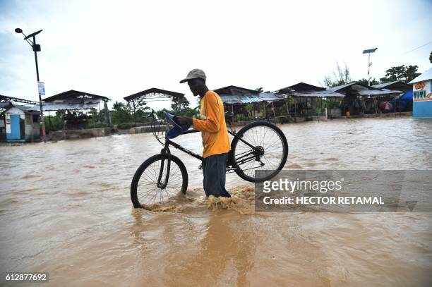 Man tries to cross the overflowing of the river Rouyonne, in the commune of Leogane Port-au-Prince, on October 5, 2016. - Haiti and the eastern tip...