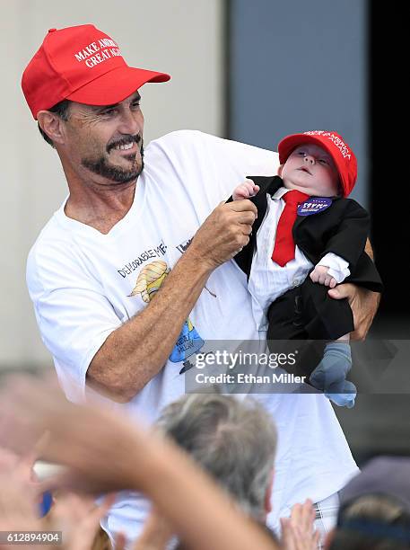 Supporter of Republican presidential nominee Donald Trump holds a baby dressed as Trump during a campaign rally at the Henderson Pavilion on October...