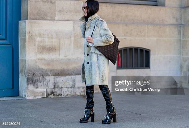 Yoyo Cao is wearing a fur coat, Louis Vuitton bag and black latex pants outside Louis Vuitton on October 5, 2016 in Paris, France.