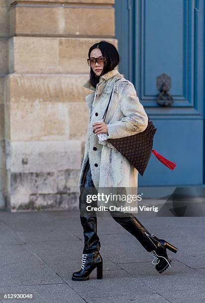 Yoyo Cao is wearing a fur coat, Louis Vuitton bag and black latex pants outside Louis Vuitton on October 5, 2016 in Paris, France.