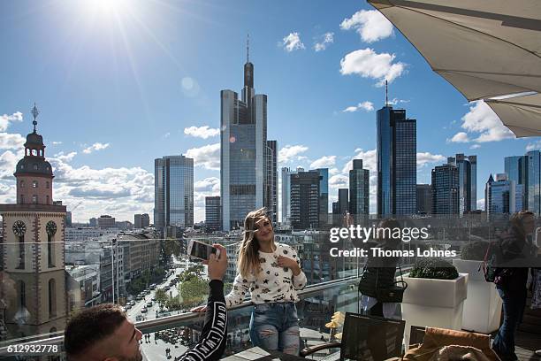 People sit at restaurant roof terrace with the skyline and finance district of Frankfurt on October 5, 2016 in Frankfurt, Germany. Banks across...