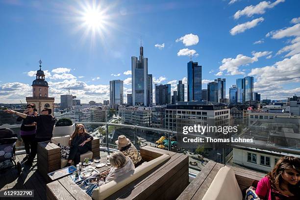 People sit at restaurant roof terrace with the skyline and finance district of Frankfurt on October 5, 2016 in Frankfurt, Germany. Banks across...