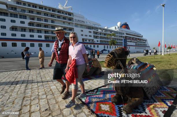 Tourists walk past camels after they disembarked the German-operated MS Europa cruise liner at La Goulette, a port on the northern edge of Tunis, on...