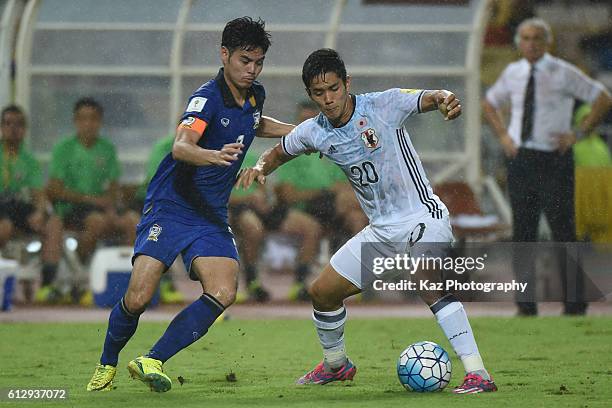 Yoshinori Muto of Japan keeps the ball under the pressure from Bunmathan Theerathon of Thailand during the 2018 FIFA World Cup Qualifier between...