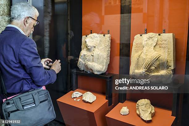 Visitor takes a picture of two busts whose faces were hammered away by Isis members at Palmyra's Museum in Syria, as part of an exhibition called...