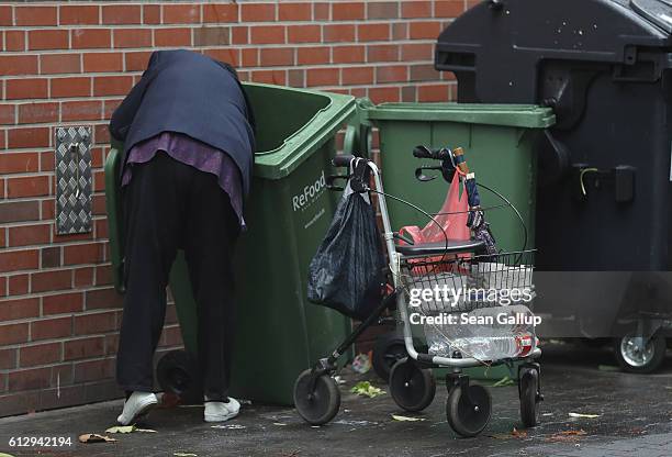 An elderly woman picks out discarded grocery items from a recycling bin behind a supermarket on October 6, 2016 in Berlin, Germany. The number of...