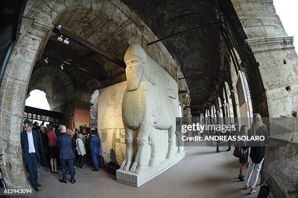 People walk past a reconstitution of the human-headed bull from the North-West Palace in Nimrud, as part of an exhibition called "Rising from...