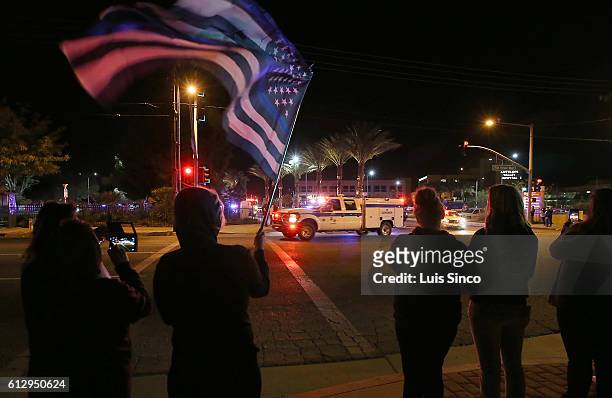 Antelope Valley residents look on as a coroner's van takes the body of Sheriff's Sgt. Steve Owen from the Antelope Valley Medical Hospital to the...
