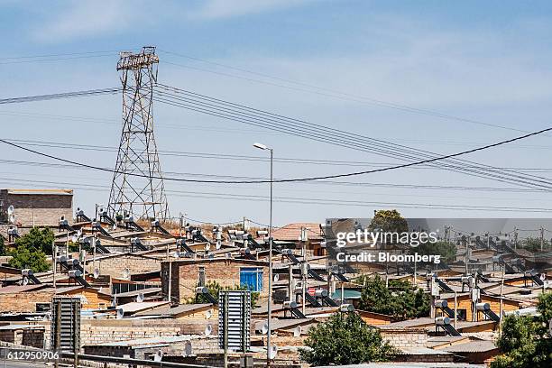 Pylon tower carries electrical power lines over residential shacks, some equipped with solar power geysers on their roofs, in the Alexandra township...