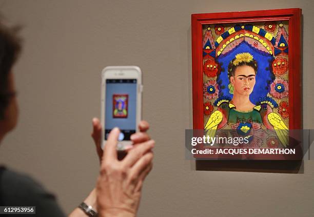 Visitor takes a picture of the painting "The Frame" by Mexican painter Frida Kahlo during the exhibition "Mexique : Diego Rivera, Frida Kahlo, Jose...