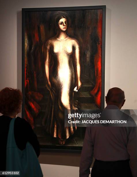 Visitors look at the painting "Portrait of Maria Asunsolo descending a staircase" by Mexican painter David Alfaro Siqueiros during the exhibition...