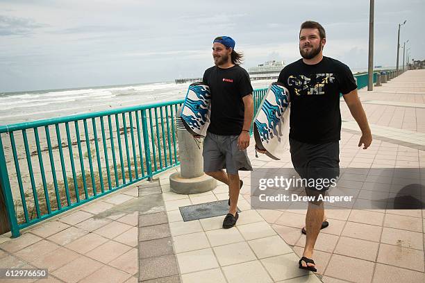 Shane Reed and Jon Anderson walk along the Daytona Beach Boardwalk carrying boogie boards, October 6, 2016 in Daytona Beach, Florida. With Hurricane...