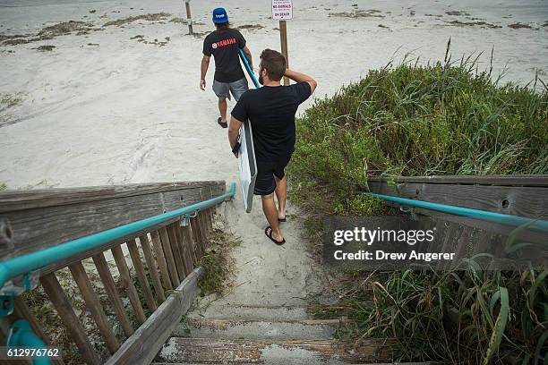 Shane Reed and Jon Anderson make their way toward the water carrying boogie boards, October 6, 2016 in Daytona Beach, Florida. With Hurricane Matthew...