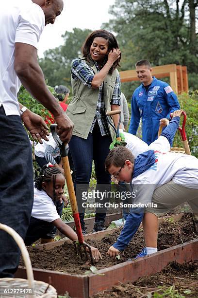 First lady Michelle Obama works with students to harvest sweet potatoes in White House Kitchen Garden on the South Lawn of the White House October 6,...