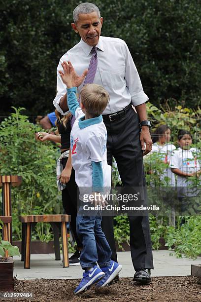 President Barack Obama gives a high-five to a student during an event to harvest the White House Kitchen Garden on the South Lawn of the White House...