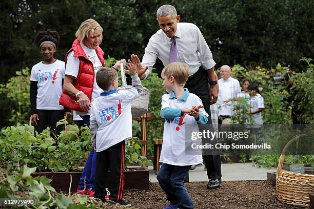 President Barack Obama gives a high-fives to students during an event to harvest the White House Kitchen Garden on the South Lawn of the White House...