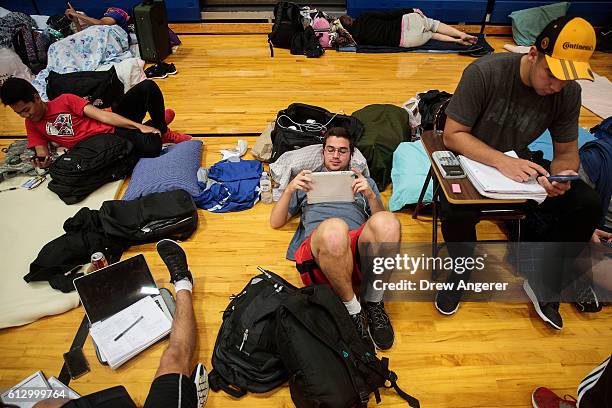 Embry-Riddle Aeronautical University student TJ Rusiniak watches weather updates on his iPad at a public shelter set up at Mainland High School,...