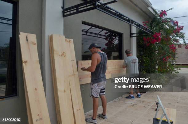 Brian Baker and son Ian board up their office in Titusville, Florida, before the landfall of Hurricane Matthew, on October 6, 2016. - Some three...