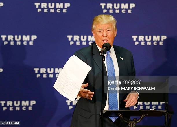 Republican presidential candidate Donald Trump tosses a piece of paper with recent polling statistics as he speaks at a town hall event on October 6,...
