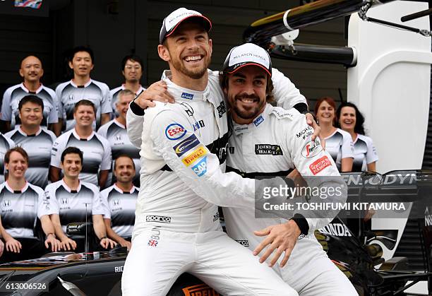 McLaren Honda's British driver Jenson Button joks with his teammate Fernando Alonso of Spain during the team's photo session at the Formula One...