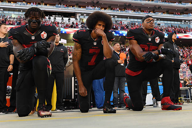 Eli Harold, Colin Kaepernick, and Eric Reid of the San Francisco 49ers kneel in protest during the national anthem prior to their NFL game against...