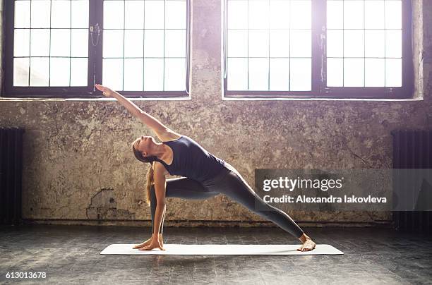 jeune femme pratiquant le yoga dans un loft urbain - yoga pose photos et images de collection