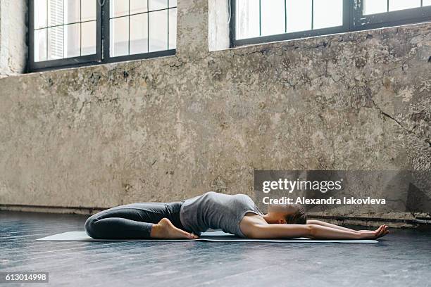 jeune femme pratiquant le yoga dans un loft urbain - supta virasana photos et images de collection