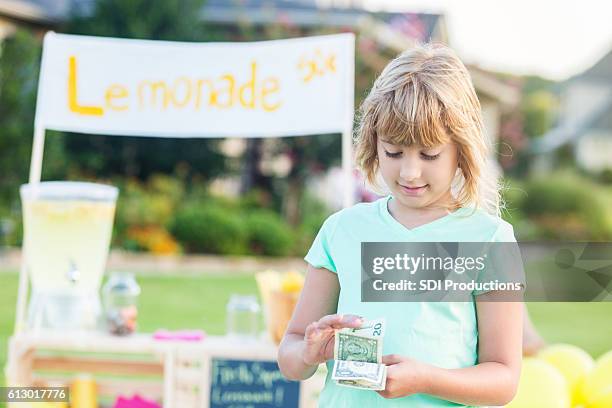 girl counts money made from lemonade sales - earnings season stock pictures, royalty-free photos & images