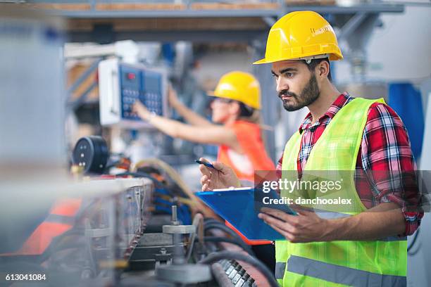 male worker in factory taking notes - manufacturing machinery stock pictures, royalty-free photos & images