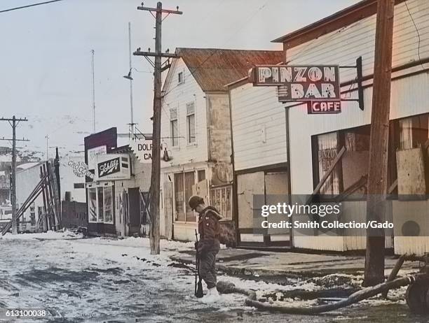 Army guards stationed on a main street in Valdez, Alaska after it was shaken by a tidal wave and earthquake, March 27, 1964. Note: Image has been...