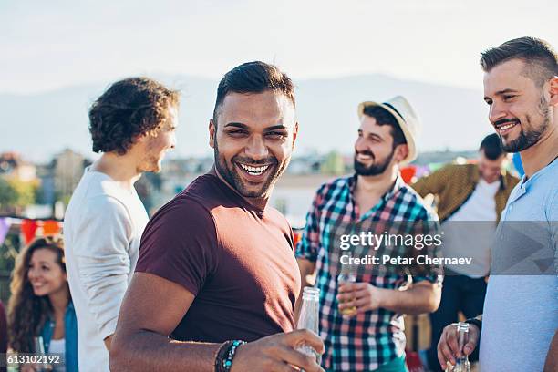 cheerful young men on a rooftop party - arab people laugh stockfoto's en -beelden