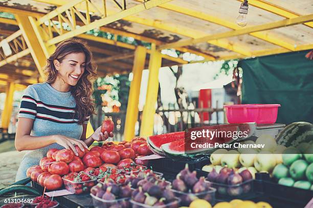 junge frau beim einkaufen auf dem bauernmarkt - landwirtschaftsmesse stock-fotos und bilder