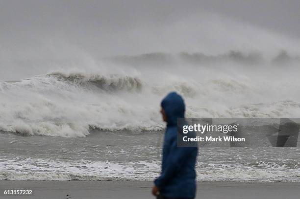 Man walks past heavy surf caused by Hurricane Matthew, October 7, 2016 on Cocoa Beach, Florida. Hurricane Matthew passed by offshore as a catagory 3...