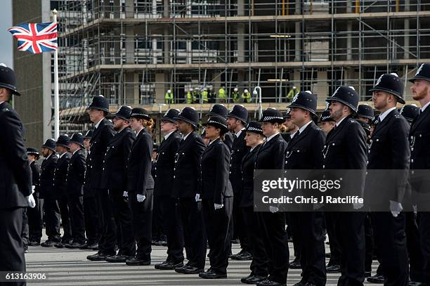 Builders on a residential building site look on at new recruits to the Metropolitan Police Service taking part in their 'Passing Out Parade' outside...