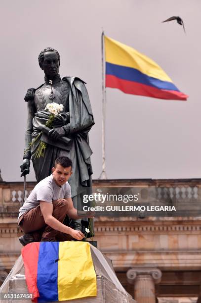 Colombian youngster places the national flag and a bunch of white flowers at the bottom of Simon Bolivar's monument to celebrate that Colombia's...