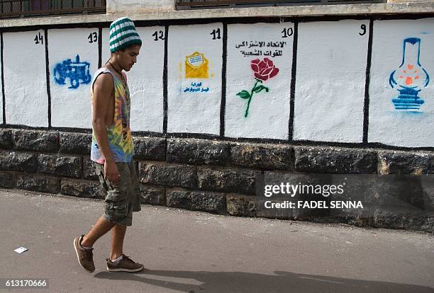 Moroccan youth walks past a wall on which are painted the symbols of the political parties running for the parliamentary elections in the Moroccan...