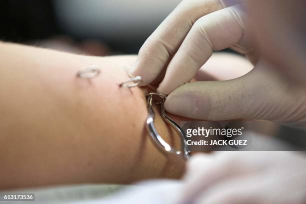 Piercer inserts a ring through the arm of a woman during the 4th Israel Tattoo Convention in the coastal city of Tel Aviv, on October 7, 2016....