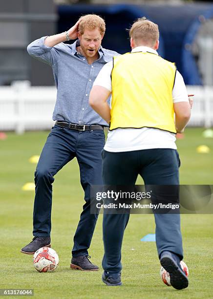 Prince Harry plays football as he attends an event to mark the expansion of the Coach Core sports coaching apprenticeship programme at Lord's cricket...