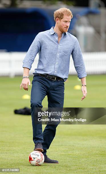 Prince Harry plays football as he attends an event to mark the expansion of the Coach Core sports coaching apprenticeship programme at Lord's cricket...