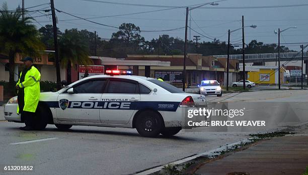 Police block a road with downed power lines after the passing of Hurricane Matthew in Titusville, Florida on October 7, 2016. Fierce Hurricane...