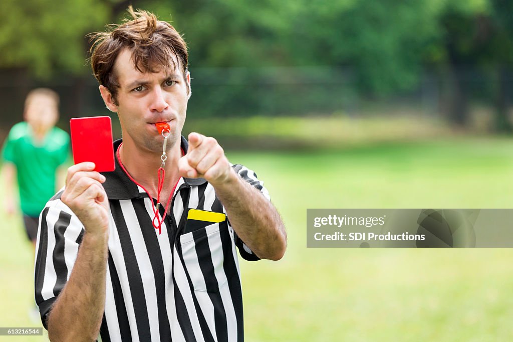 Soccer referee points and holds up red card