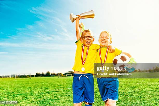 fußball-jungs feiern sieg mit medaillen und fußball - child trophy stock-fotos und bilder