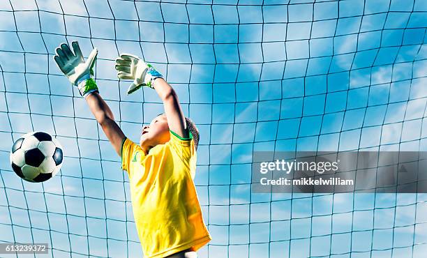 torwart springt, um fußball aus dem tor zu blockieren - soccer glove stock-fotos und bilder