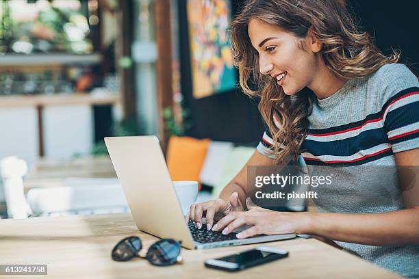 mujer joven trabajando en una computadora portátil - navegar por la red fotografías e imágenes de stock